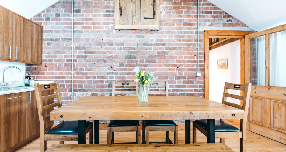 Dining area with brick wall, table, and chairs.