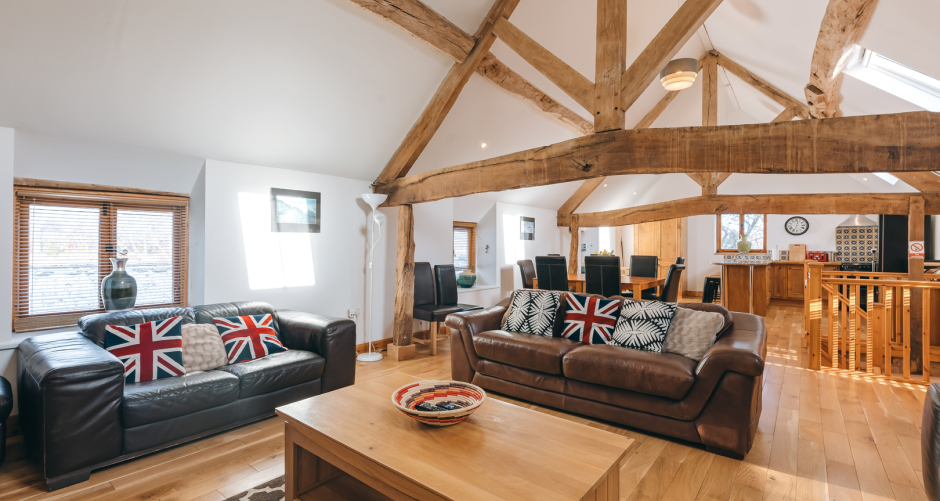 Living room with sofas, wooden beams, and table.