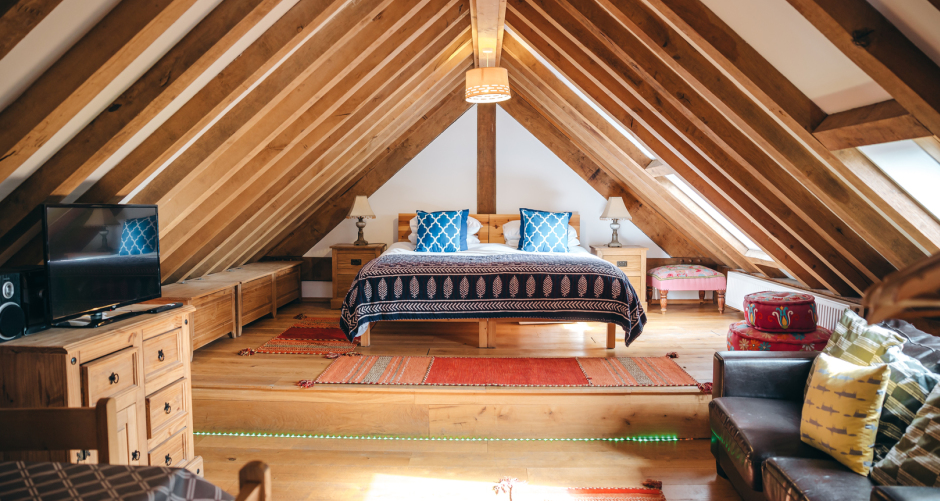 Attic bedroom with wooden beams and furniture.