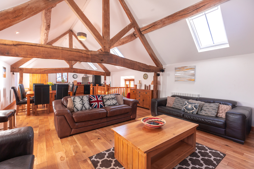 Living room with wooden beams, sofas, and table.