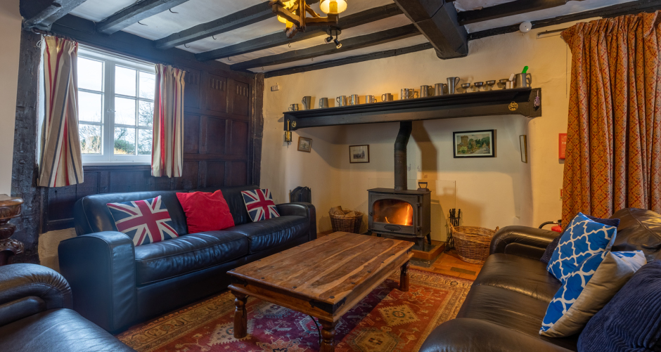 Living room with fireplace, sofas, and wooden beams.