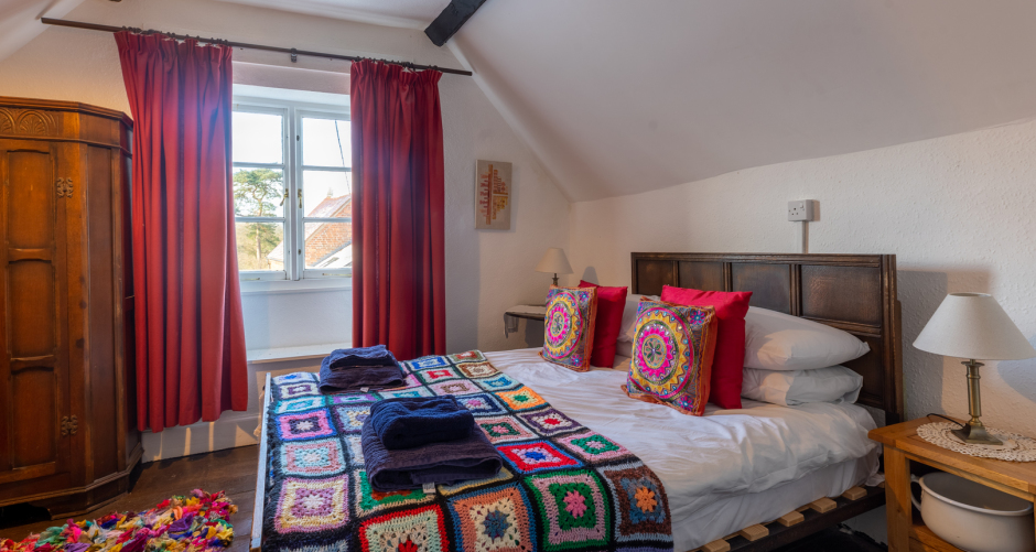 Bedroom with bed, curtains, and wooden furniture.